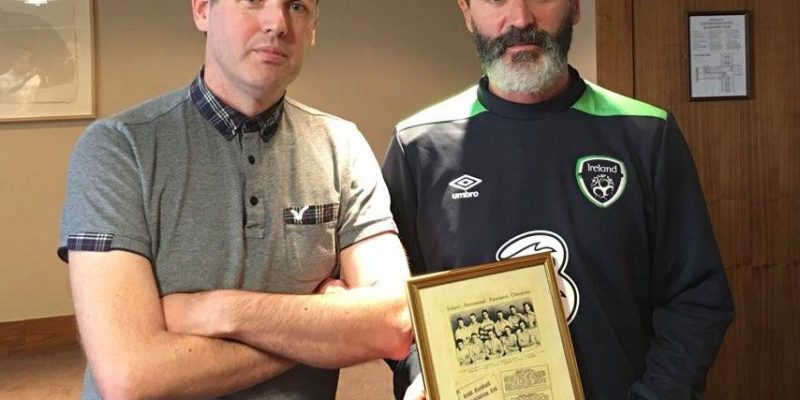 Roy Keane holding a sign posing for the camera